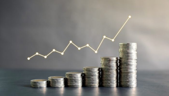 Stack of Thailand coins on black wooden table with profit graph,